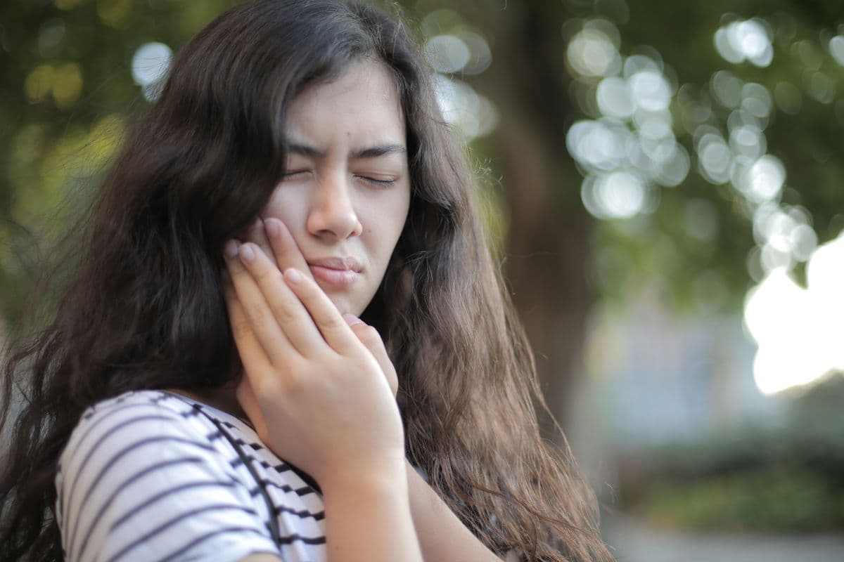 sensitive teeth Kharghar woman wincing at tooth sensitivity before a check-up at Reform Dental Clinic Sector 15