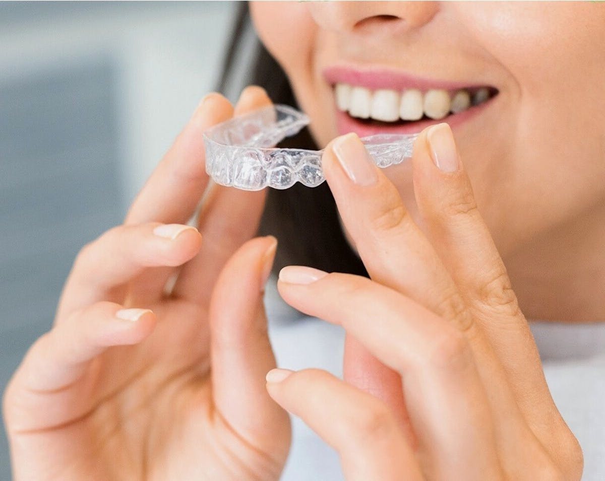 braces vs aligners Kharghar woman holding a clear dental aligner at Reform Dental Clinic Sector 15